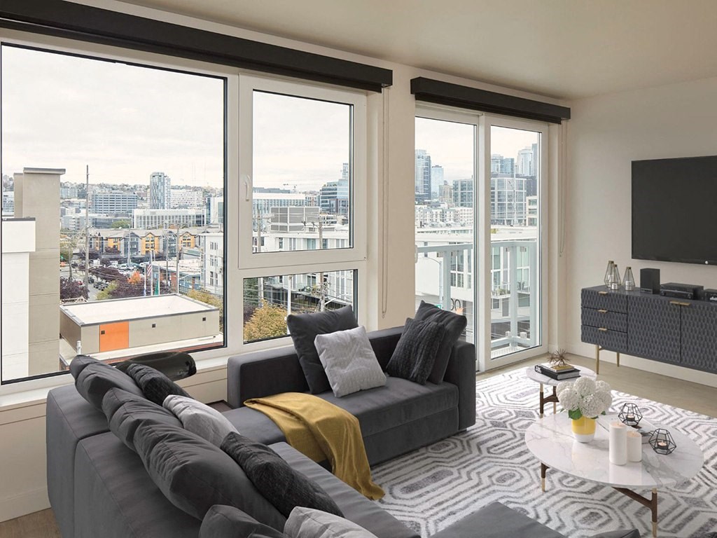 a living room with a gray couch and a view of the city