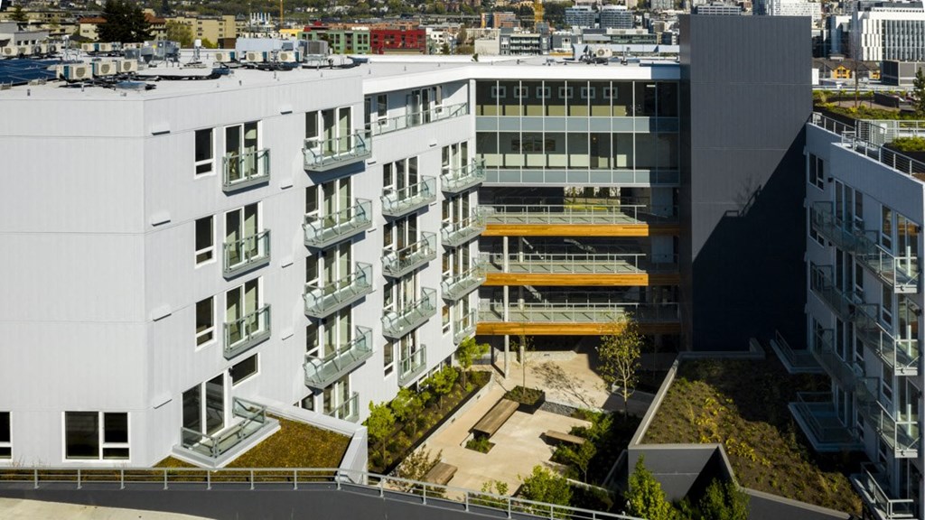an aerial view of a large white building with balconies and a green roof