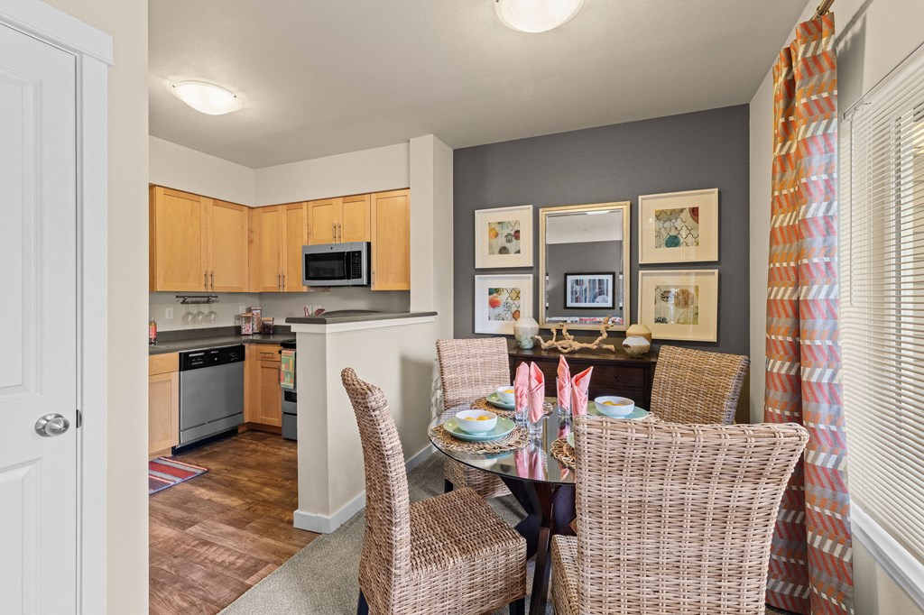 a dining room table with chairs and a kitchen in the background