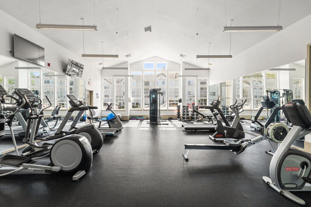 a gym with cardio equipment and weights on the floor