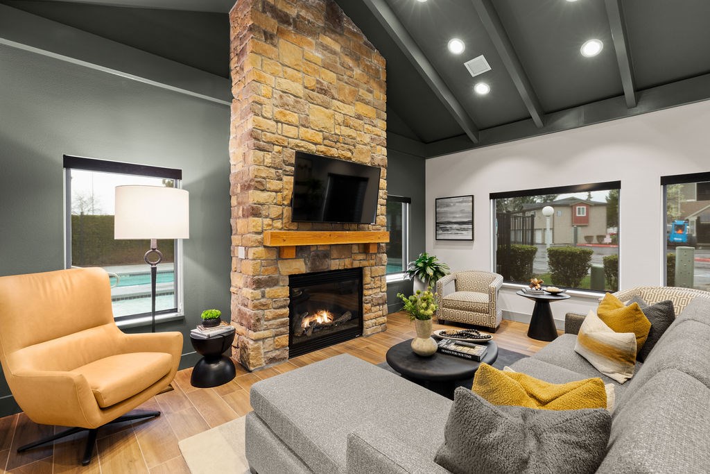 A living room with a stone fireplace and a grey couch.