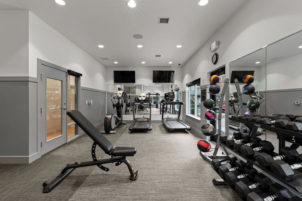 A gym with a variety of equipment including weights and a bench.