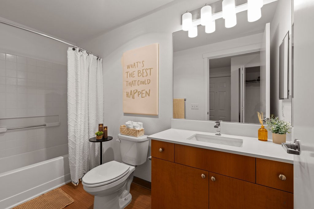 A bathroom with a toilet, sink, and mirror.