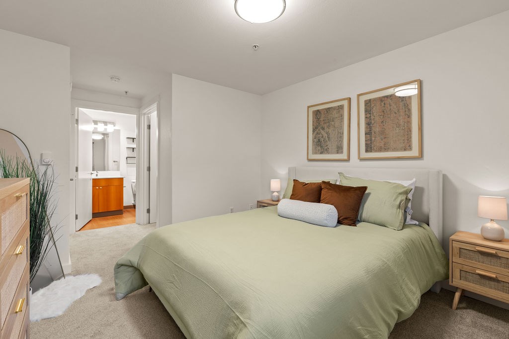 A bedroom with a bed, nightstands, and two framed pictures on the wall.