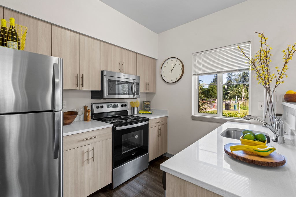 A kitchen with a stainless steel refrigerator, microwave, oven, and sink.
