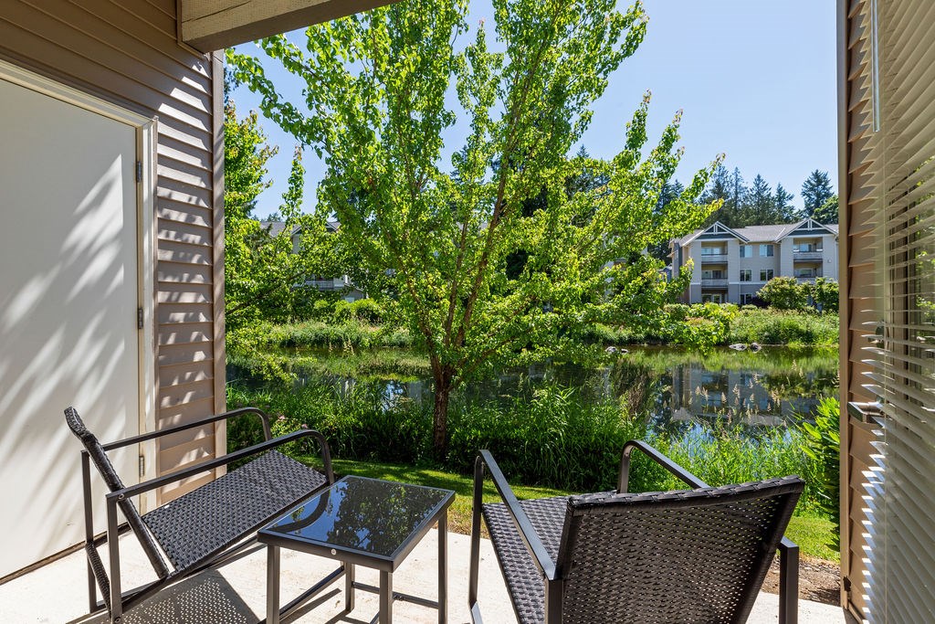 A patio with a table and chairs overlooking a pond.