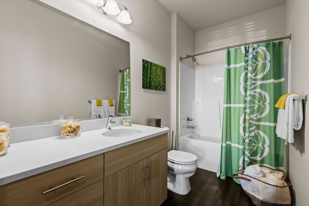 A bathroom with a green shower curtain and a white toilet.