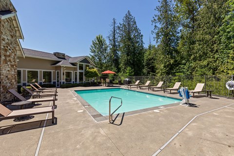 A swimming pool surrounded by lounge chairs and trees.