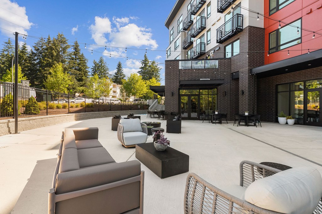 an outdoor patio with couches and tables in front of a building