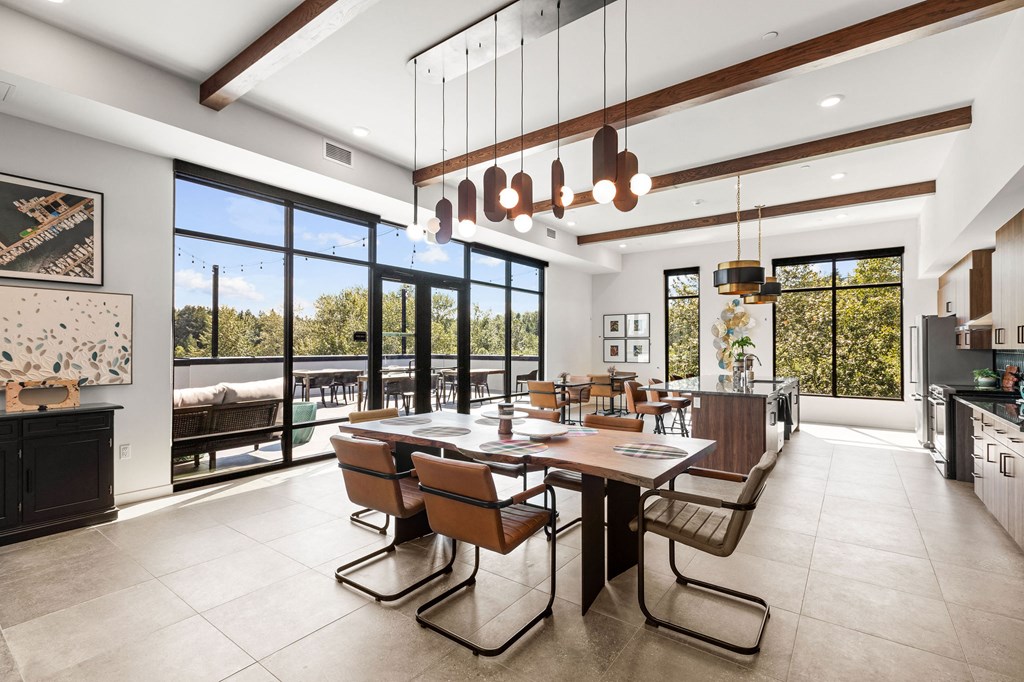 a dining room with a long wooden table and chairs and large windows