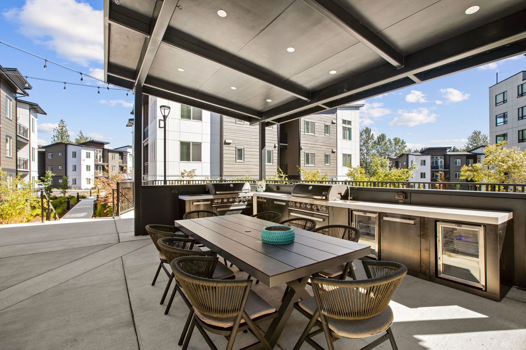 a communal patio with a table and chairs and a bar and buildings