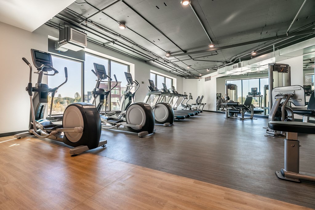 a gym with cardio machines and weights on a wooden floor