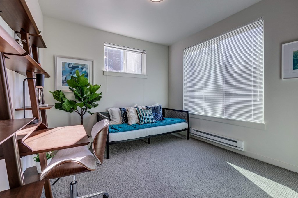 a living room with a couch and a desk and a window