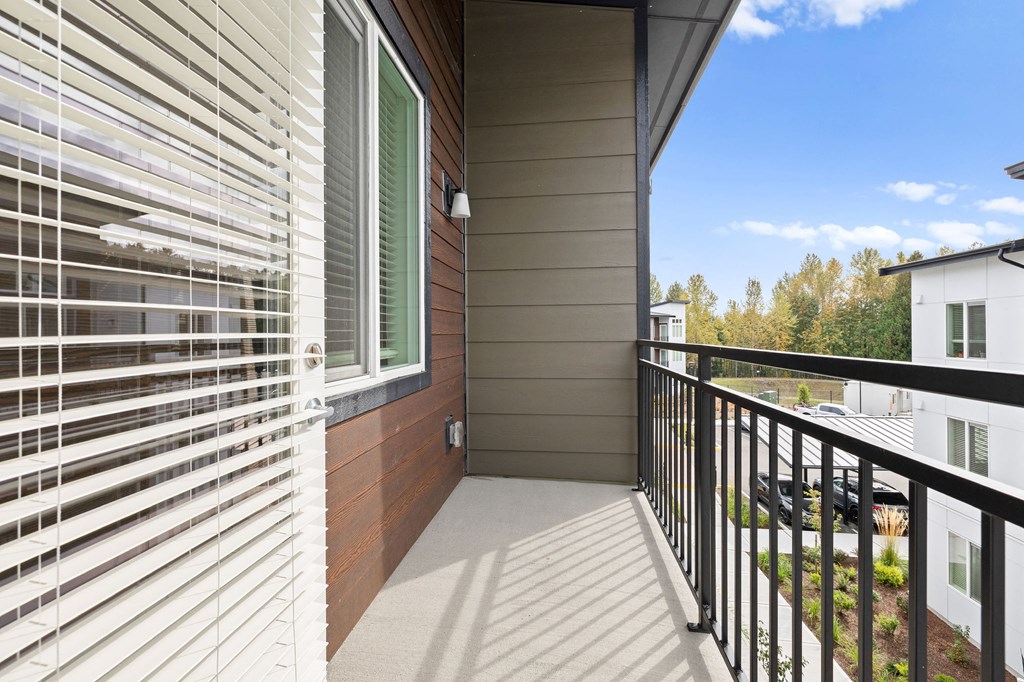 the balcony of a home with white blinds on the side of a house