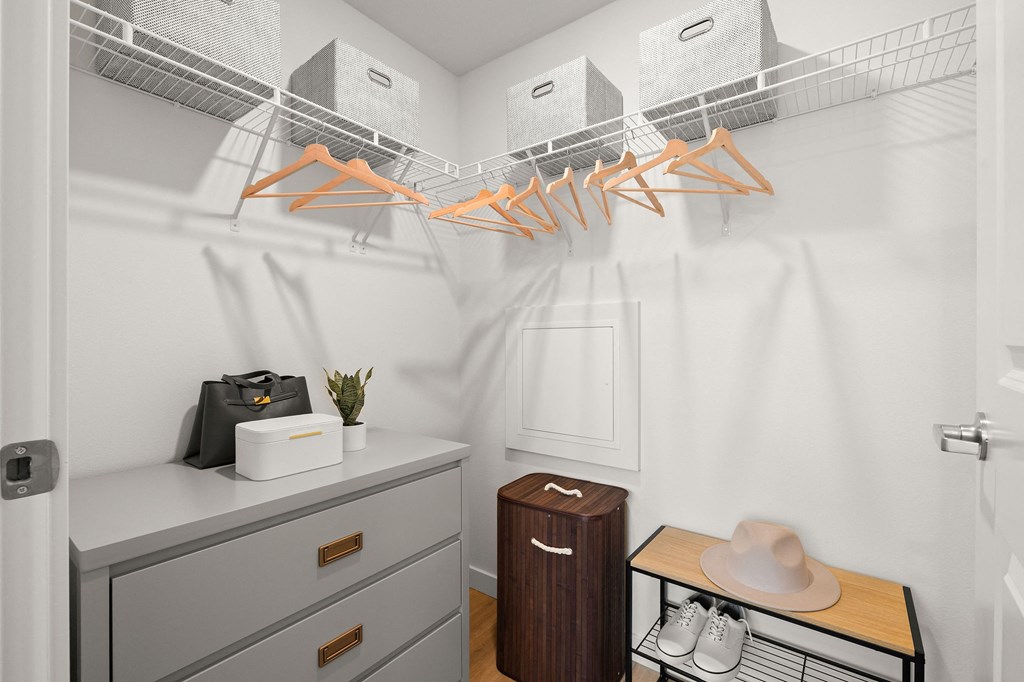 a walk in closet with white walls and a rack with shoes and a hat