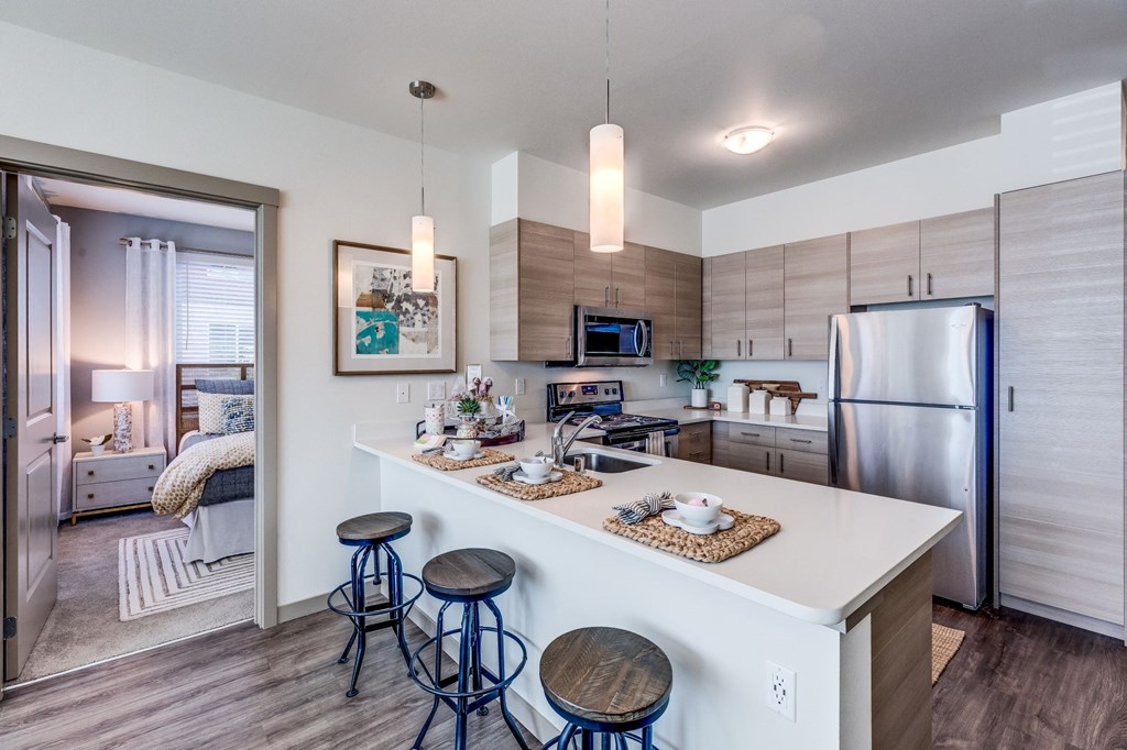 a kitchen with a island and stools and a stainless steel refrigerator