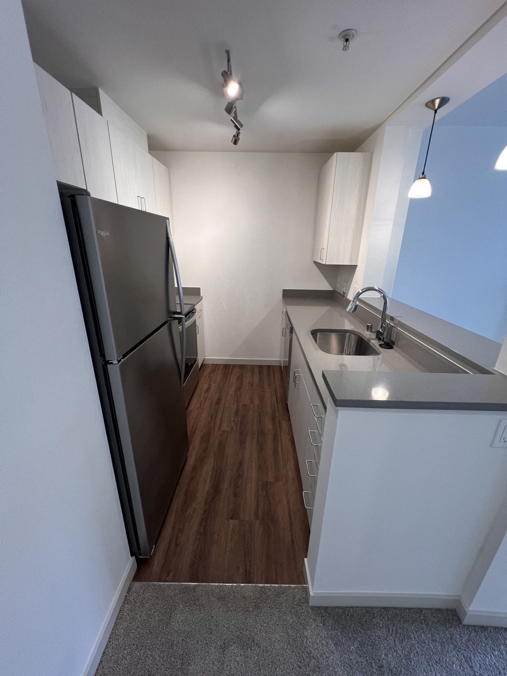 an empty kitchen with a stainless steel refrigerator and sink