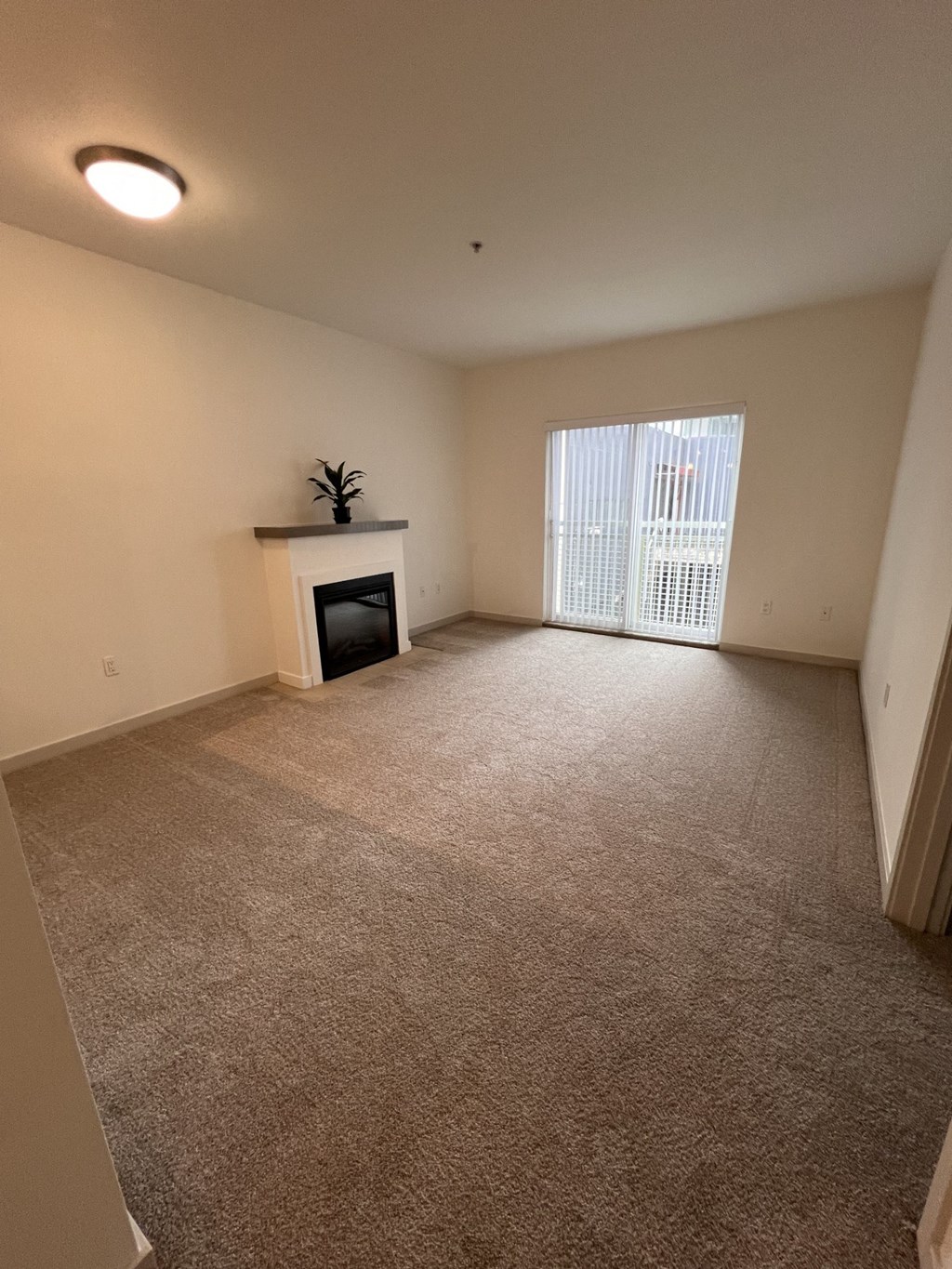 an empty living room with a fireplace and a window