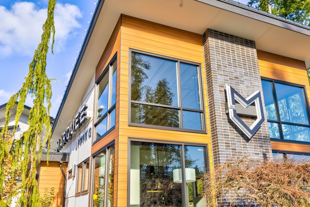 the front of a building with glass windows and a sign on the side