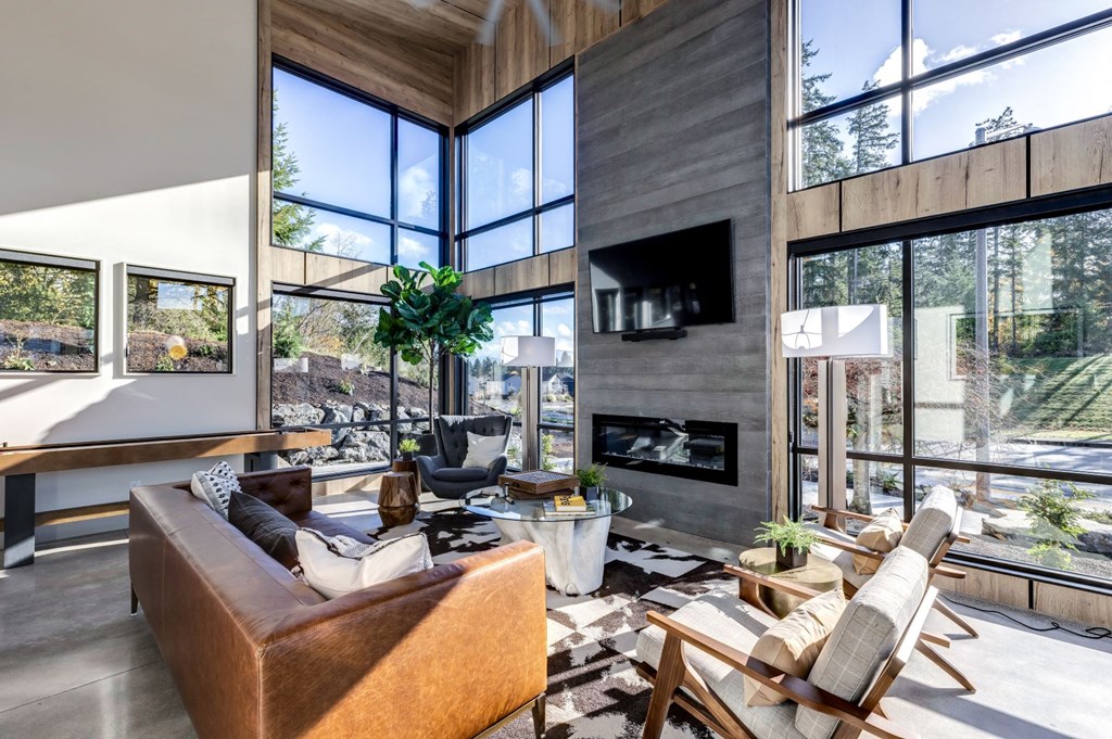 a living room with couches and a fireplace and large windows