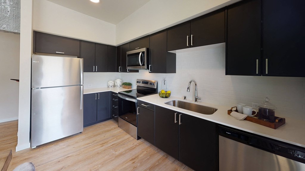 a kitchen with black cabinets and a stainless steel refrigerator