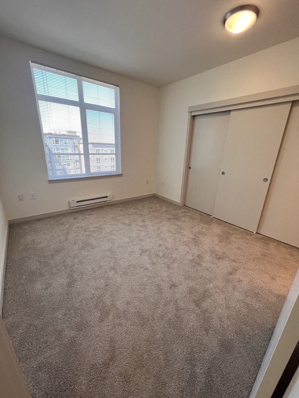 an empty living room with a window and a closet