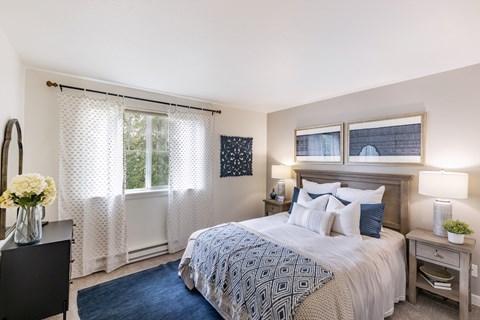 A bedroom with a large bed and a window with curtains.