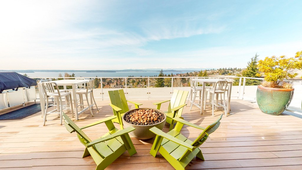 a deck with green chairs and tables overlooking the ocean