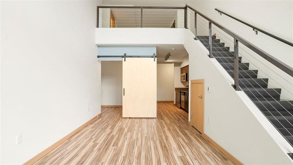 an empty living room with a staircase and wood flooring