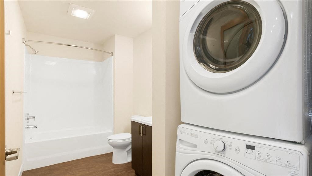 a white washer and dryer in a bathroom with a toilet