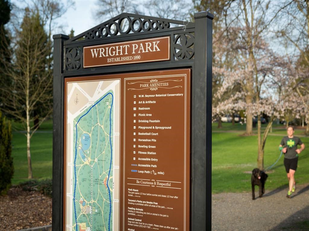 a man walks his dog past a wright park sign