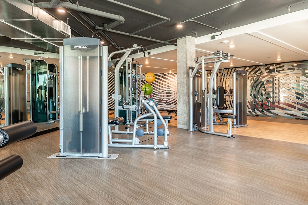 a gym with cardio machines and weights in a building with a wall of graffiti