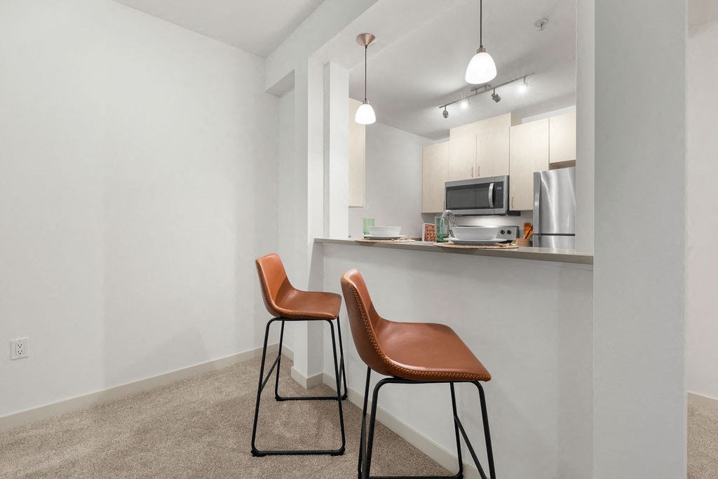 a kitchen with two stools in front of a bar with two chairs