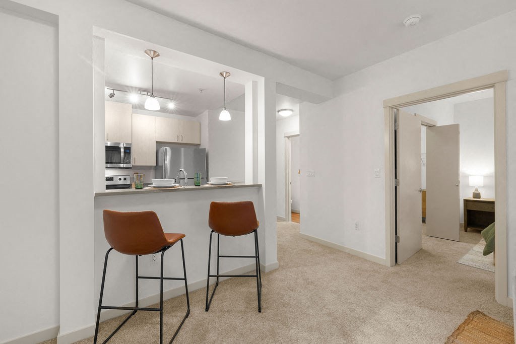 a kitchen and bar with two stools in a living room