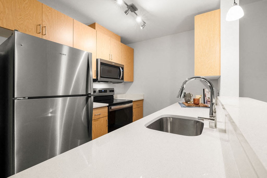 A kitchen with a stainless steel refrigerator, microwave, and sink.