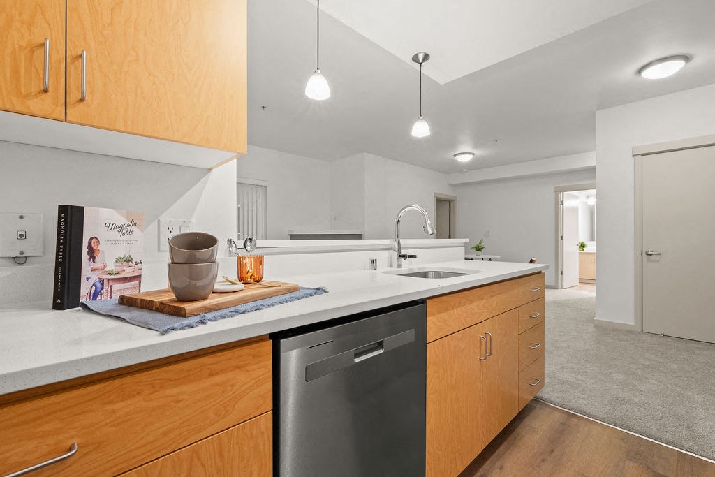 A modern kitchen with wooden cabinets and a stainless steel dishwasher.