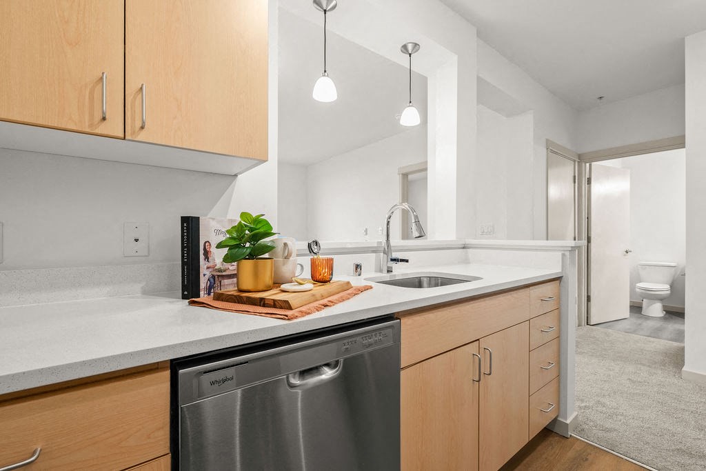 A modern kitchen with wooden cabinets and a stainless steel dishwasher.
