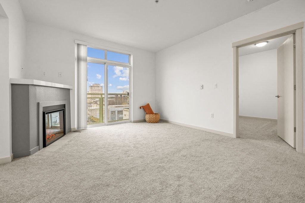 A large, empty room with a fireplace and a window overlooking a cityscape.