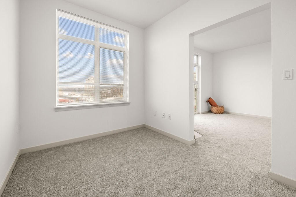 A room with a large window and a carpeted floor.