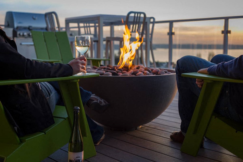 a glass of wine sits on a table next to a fire pit