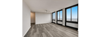 an empty living room with a ceiling fan and a view of the city