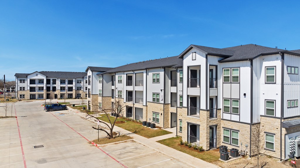 A parking lot is in front of a building with multiple stories at SOSA at Palo Alto Apartments, Texas, 78224