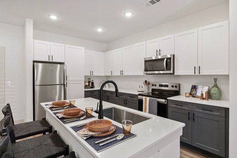 A kitchen with a white counter top and black chairs.
