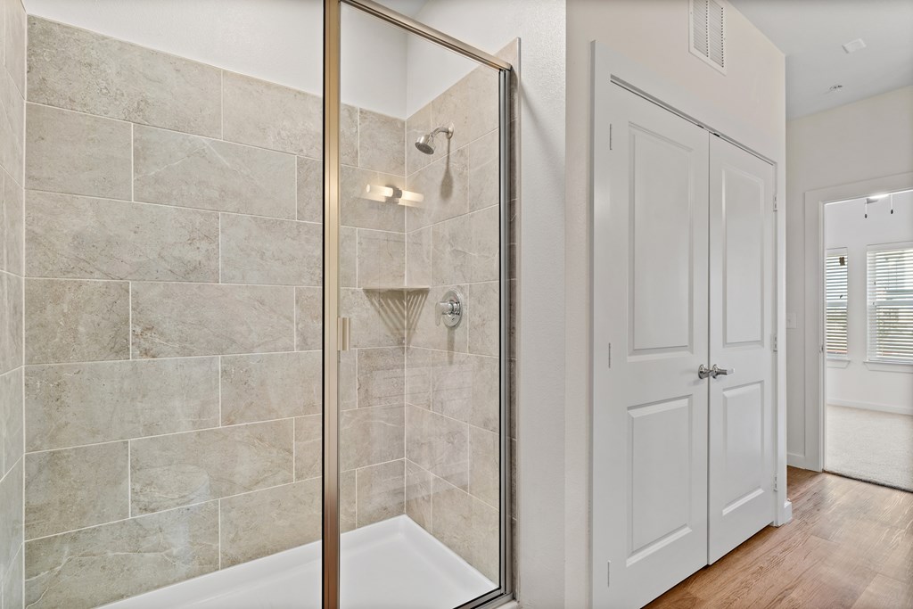 A bathroom with a walk-in shower and a white door at SOSA at Palo Alto Apartments, Texas, 78224