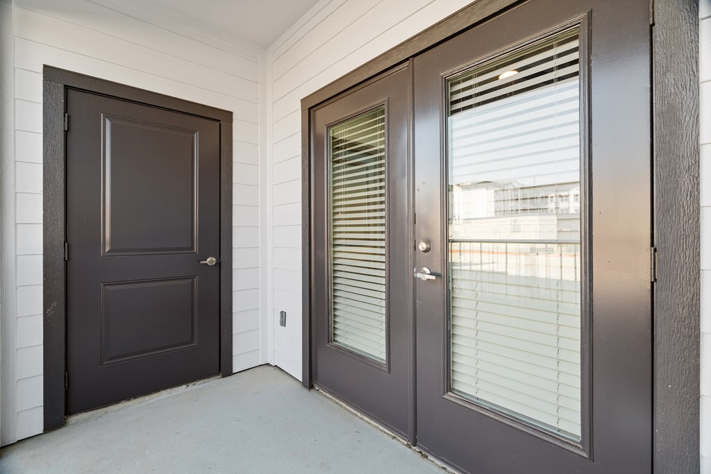 A brown door is on the left and a brown door with blinds is on the right at SOSA at Palo Alto Apartments, San Antonio