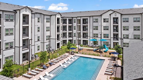 Outdoor pool with sundeck and playground at Tapestry Orem Apartments, Houston, TX