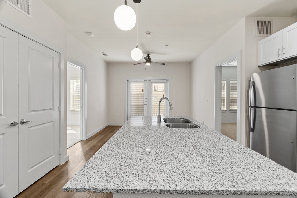 A kitchen with a white tile floor and a stainless steel refrigerator. at SOSA at Palo Alto Apartments, San Antonio, TX, 78224