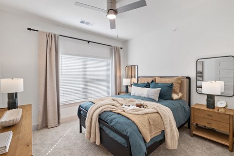 A bedroom with a large bed and a ceiling fan at Enclave Creedmoor Apartments, Texas, 78610