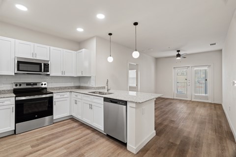 A modern kitchen with white cabinets and stainless steel appliances.