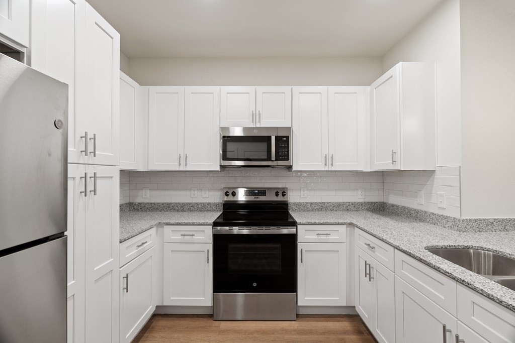 A kitchen with white cabinets and a black stove top oven at SOSA at Palo Alto Apartments, San Antonio, Texas